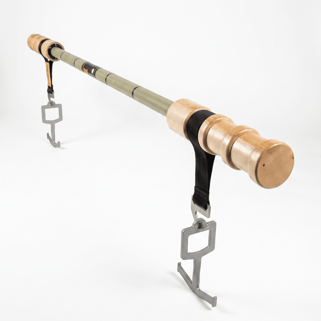 A bamboo pole with light natural wood end caps, a black strap, and two silver metal hanging hooks, photographed on a clean white studio background.