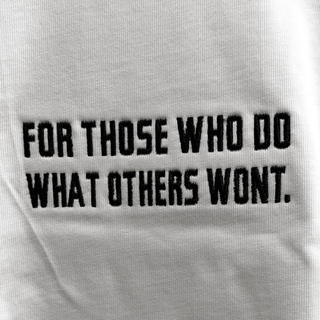 Close-up detail of the embroidered For Those Who Do What Others Won&