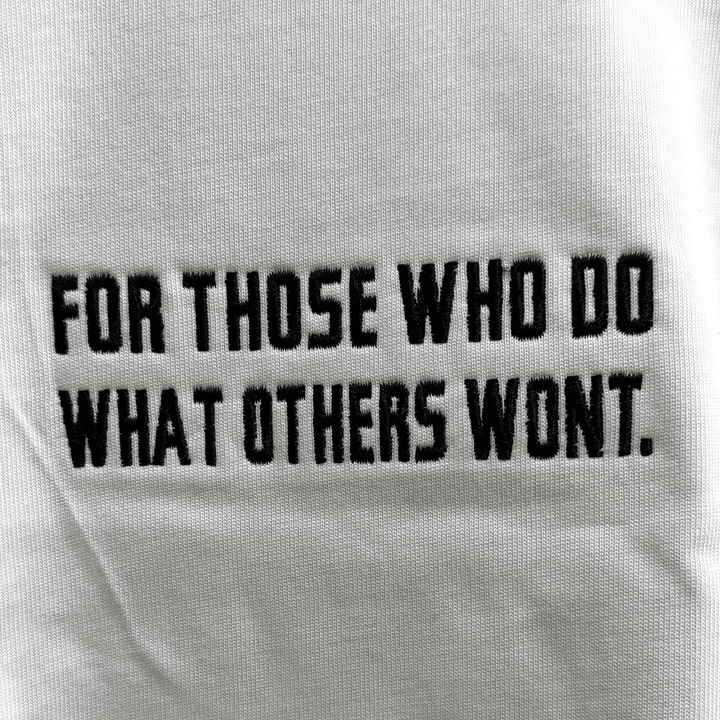 Close-up detail of the embroidered For Those Who Do What Others Won&