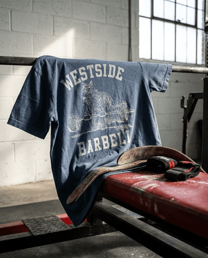 Westside Barbell washed denim t-shirt draped over red competition bench with leather lifting belt