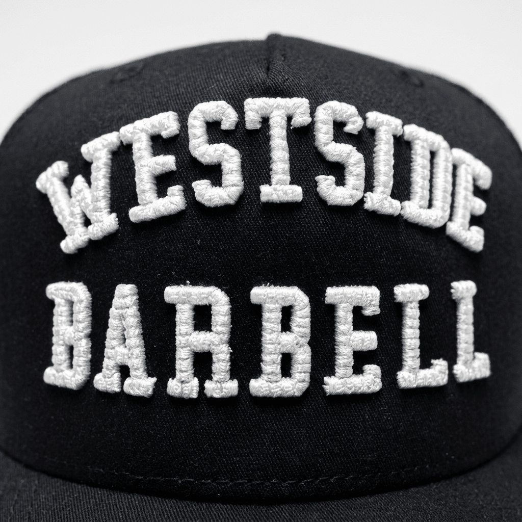 Close-up of the raised white WESTSIDE BARBELL embroidery on the black EST. 1972 snapback