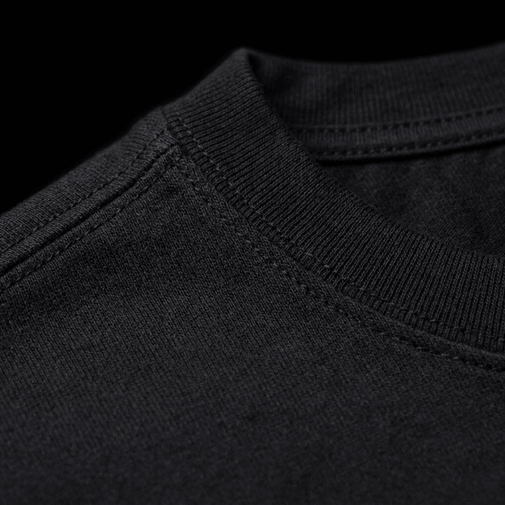 Macro close-up of the black Westside Barbell EST. 1972 heavyweight vintage tee showing 7.5 oz cotton weave texture, double-stitched neckband, and shoulder taping construction