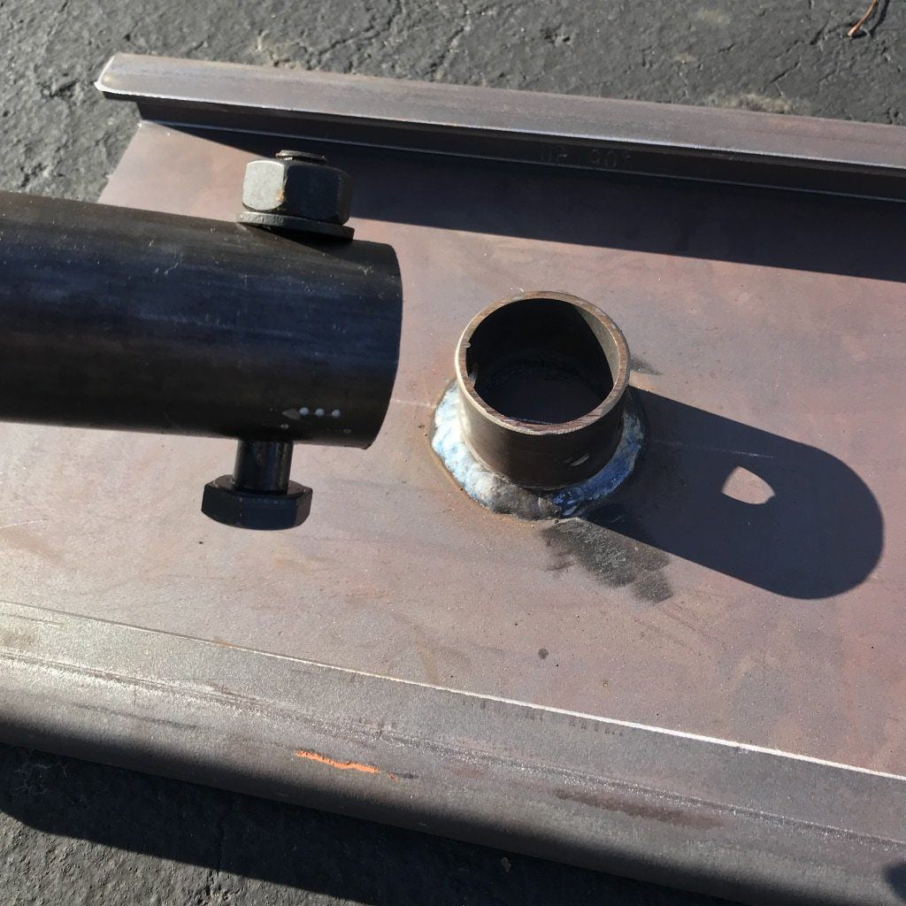 Detached weight horn and bolt beside the welded socket on the raw steel drag sled.